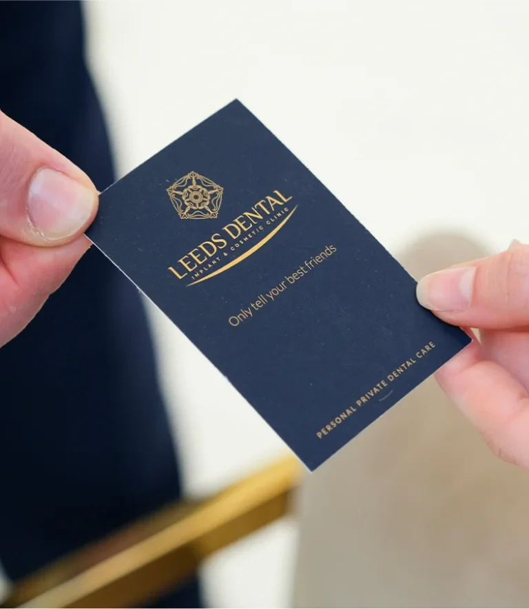 A premium business card for Leeds Dental Implant & Cosmetic Clinic, featuring gold lettering and the slogan 'Only tell your best friends.