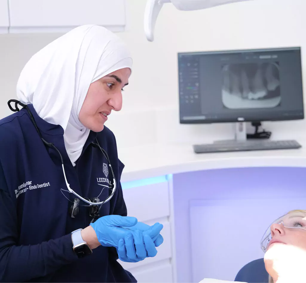 Restorative dentist at Leeds Dental Clinic consulting with a patient about dental crown treatment, including options for porcelain crowns, tooth-coloured restorations, and crown placement procedure, with a dental X-ray showing underlying tooth structure and decay used to assess suitability for a dental crown.