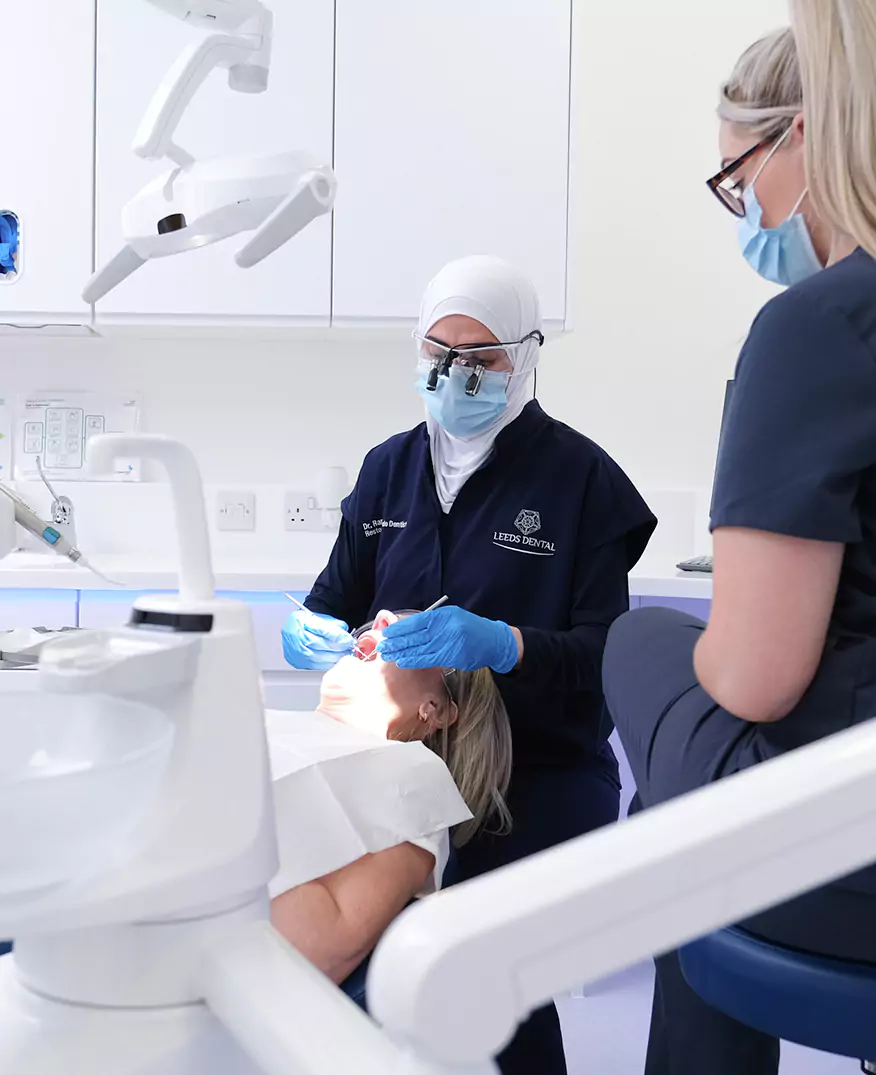 A dentist performing a dental examination on a patient while a dental assistant observes.