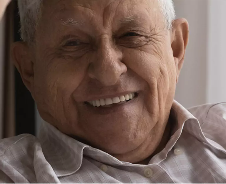 An elderly man with a bright smile, showing his healthy teeth and happiness.