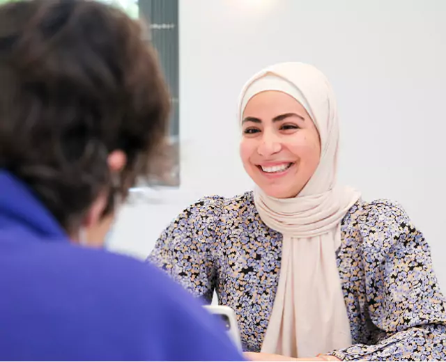 Smiling woman in a hijab engaging in a friendly conversation with a client.