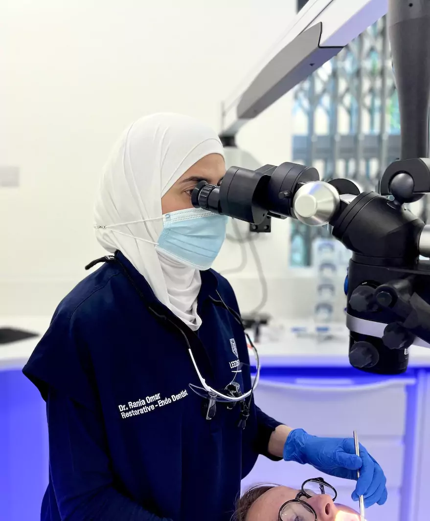 Dr. Rania Omar, a restorative endodontist at Leeds Dental, using a dental microscope to perform a root canal procedure on a patient.