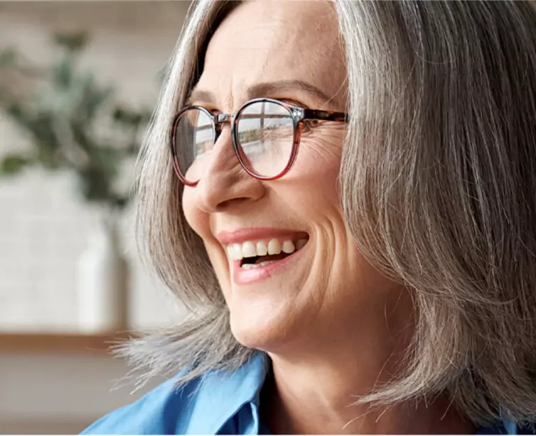 A happy senior woman with glasses smiling brightly.